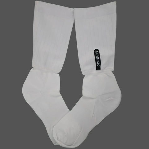 A pair of white crew socks laid flat on a solid dark gray background, featuring a small black vertical brand tag on the right sock.