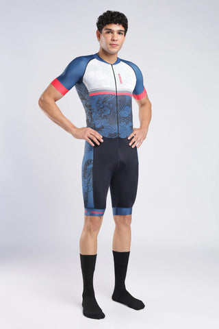 A man modeling a short-sleeve full-zip cycling suit with a blue, white, and red dragon pattern, paired with black socks, against a light gray studio background.