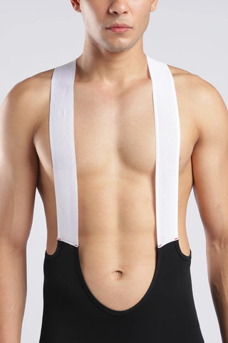 A close-up of a man wearing a black bib-style athletic top with wide white shoulder straps, shown against a light gray studio background.