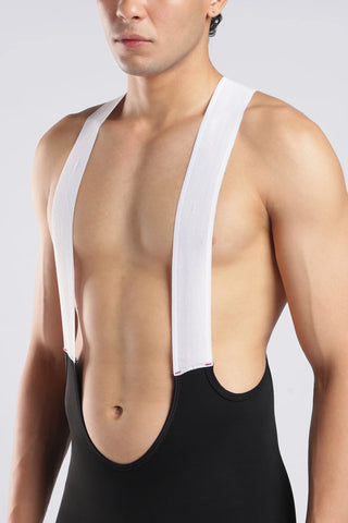 A close-up of a male model wearing a white athletic bib-style top with wide shoulder straps and a black lower torso panel, photographed against a light gray studio background.
