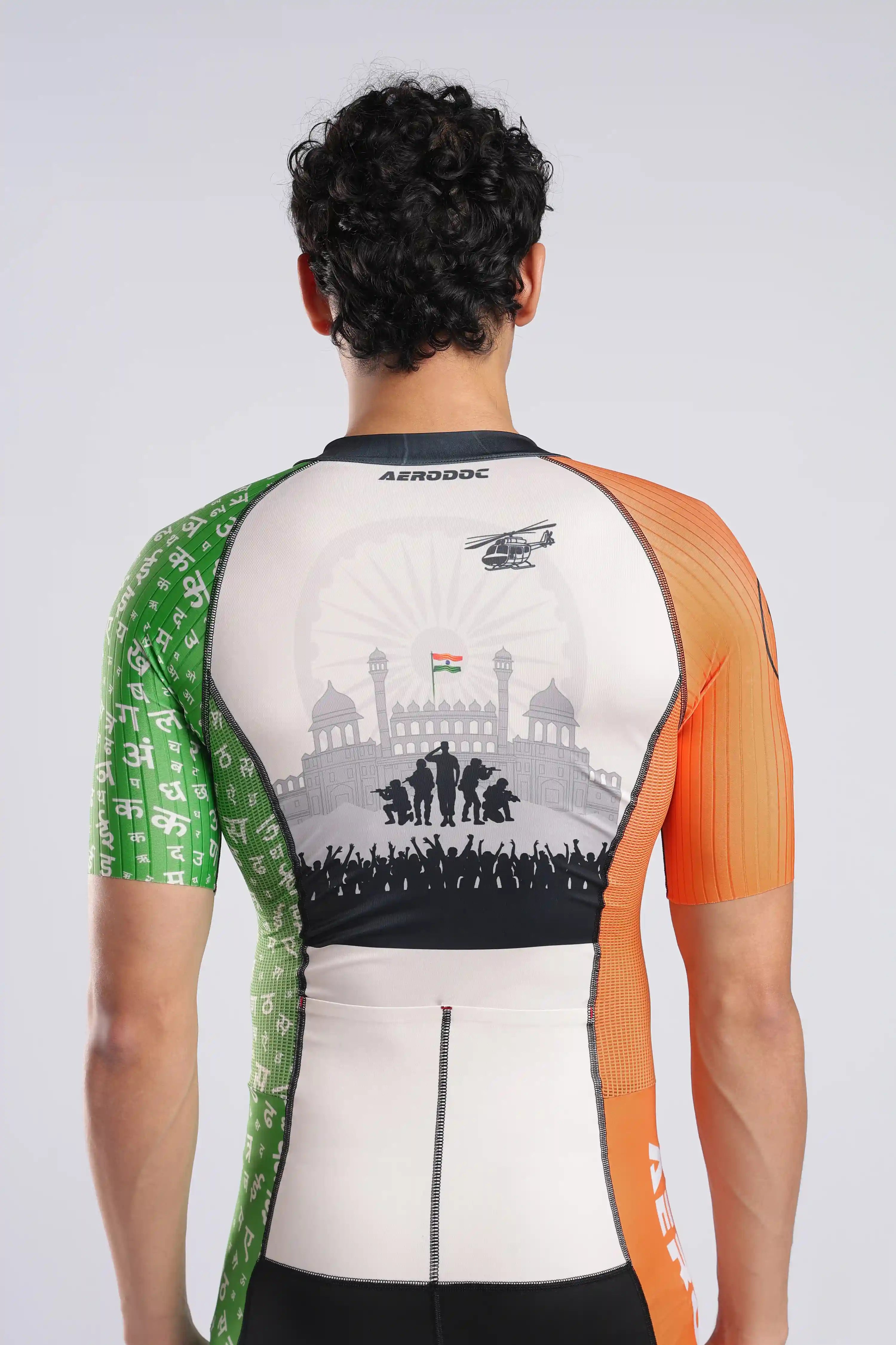 A male model wearing a AERODOC trisuit. The trisuit features a white center with a faint map graphic, orange sleeves, and green patterned sides, with the Indian flag colors (saffron, white, and green) running vertically model back view