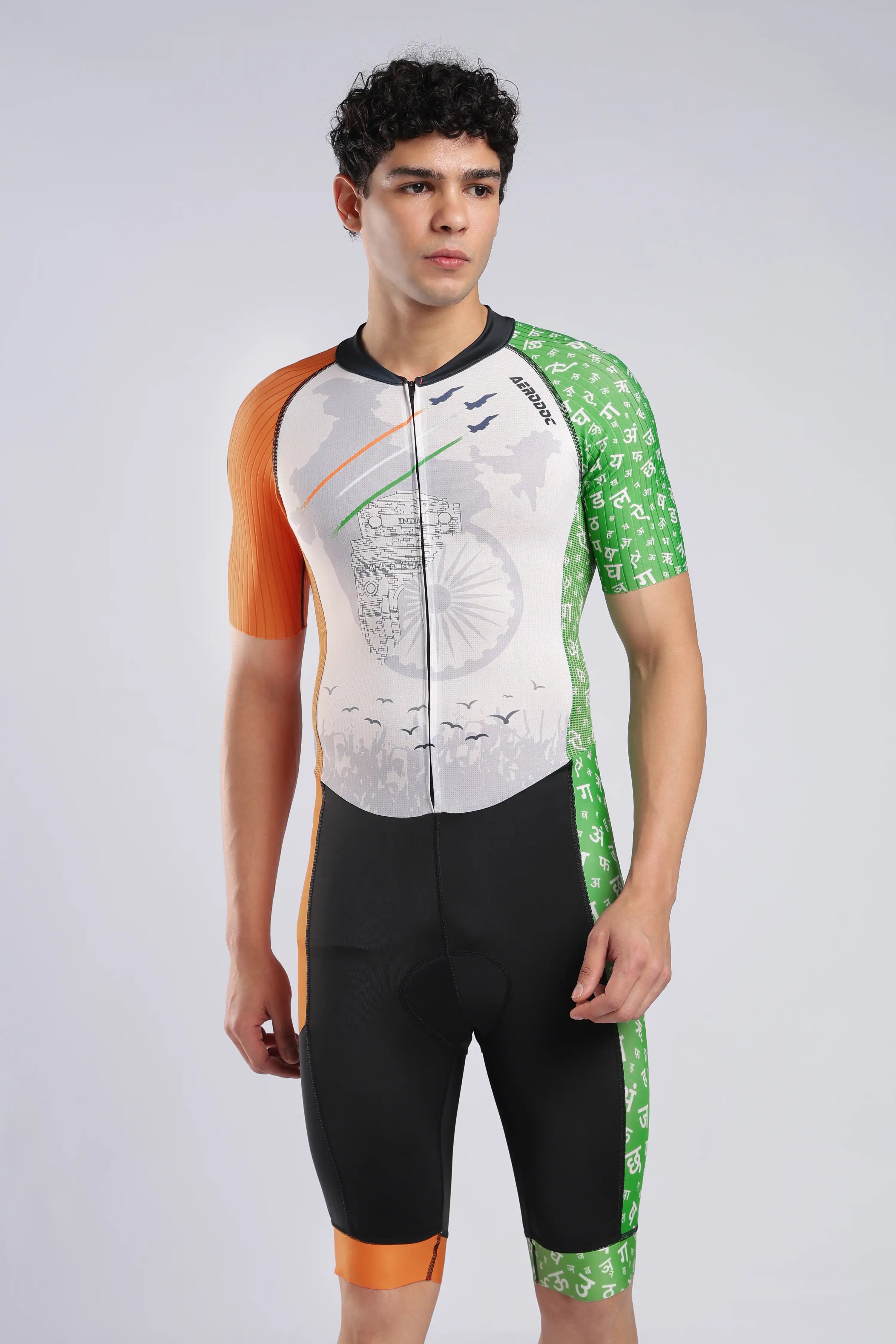 A male model wearing a AERODOC trisuit. The trisuit features a white center with a faint map graphic, orange sleeves, and green patterned sides, with the Indian flag colors (saffron, white, and green) running vertically.