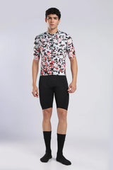 Aerodoc glitch cycling jersey a male model wearing a short-sleeve cycling jersey with a white, black, and red abstract pattern, paired with black cycling shorts, black socks, and black shoes, standing against a light gray studio background.