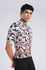 A man wearing a short-sleeve aerodoc glitch cycling jersey with a black, white, and red pixelated pattern, paired with black cycling shorts, photographed against a light gray studio background.