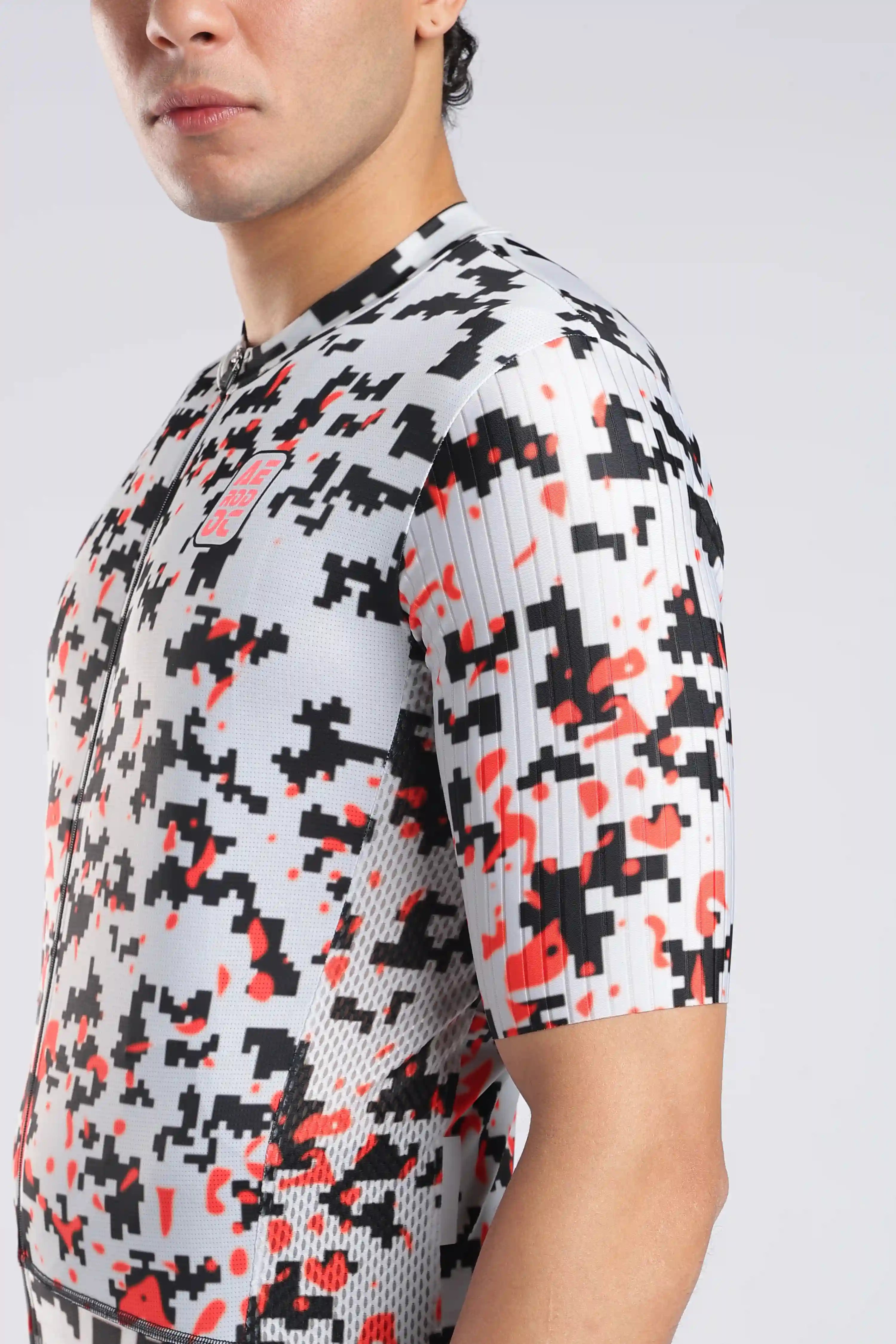 Aerodoc cycliung jersey a close-up side view of a man wearing a short-sleeve cycling jersey with a pixelated digital camouflage pattern in black, red, and white.