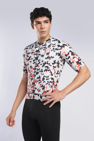 A man modeling a short-sleeve cycling jersey with a white, black, and red camouflage pattern, paired with black cycling tights, against a light gray studio background.