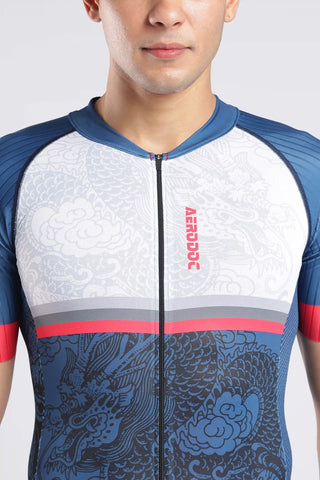 A close-up of a man wearing a short-sleeve tyrisuit with a white upper section, blue lower section, and dragon pattern. The aerodoc trisuit features a vertical red 'AERODOC' logo on the chest.