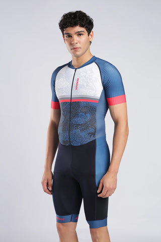 A close-up of a man wearing a short-sleeve trisuit with a white upper section, blue lower section, and dragon pattern. The aerodoc trisuit features a vertical red 'AERODOC' logo on the chest. Side view